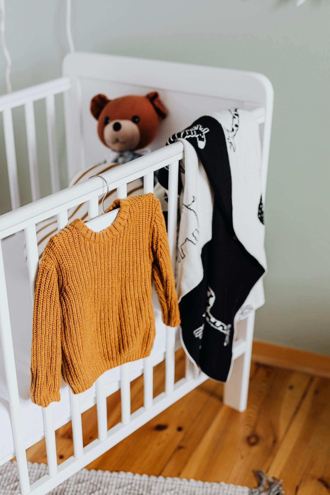 Charming baby room scene with knit sweater and teddy. Cozy and inviting.
