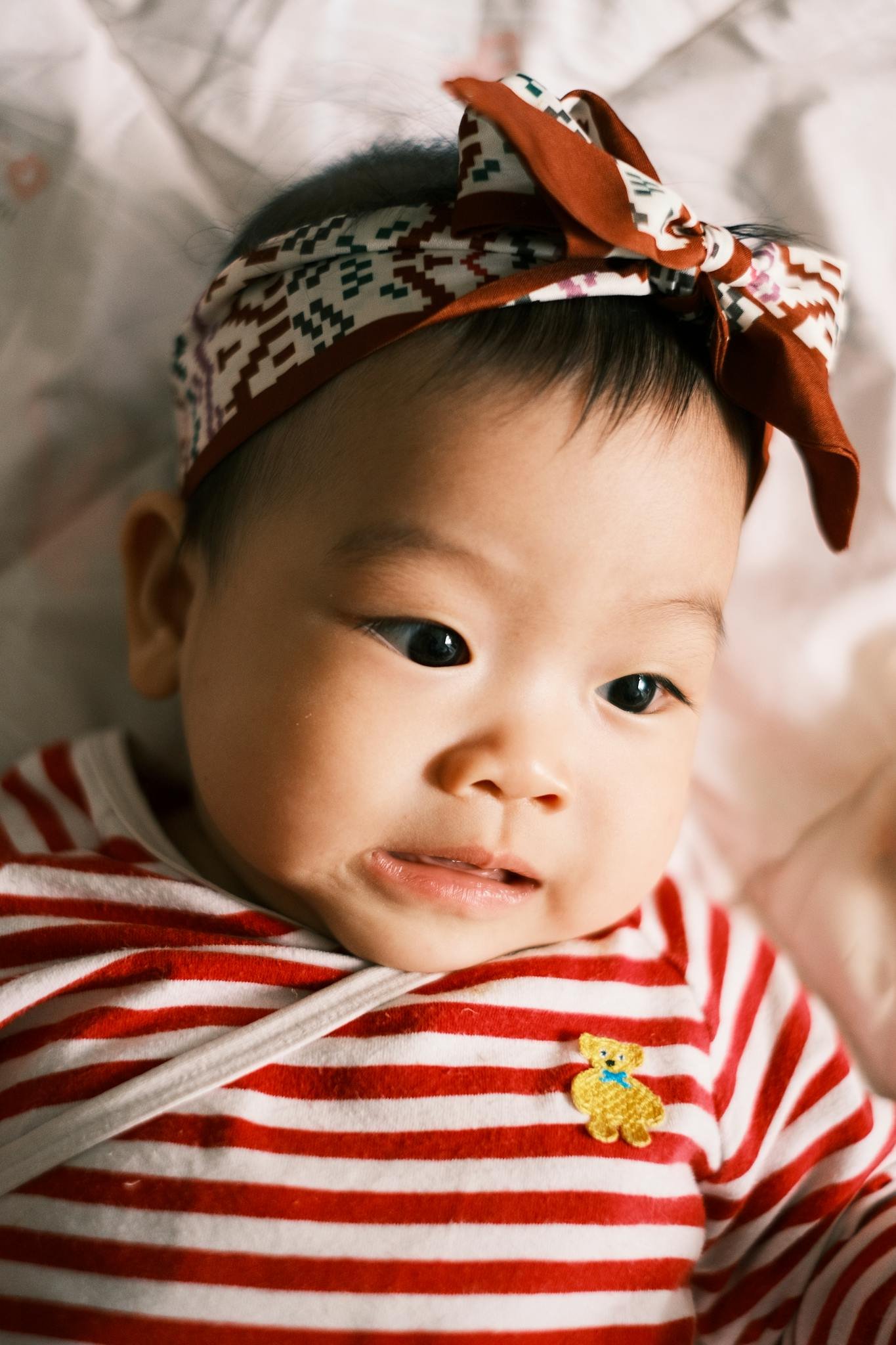 Cute baby with headband and red stripes lying comfortably, perfect stock for parenting themes.